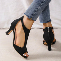 Black suede T-strap heeled sandals with back zippers.