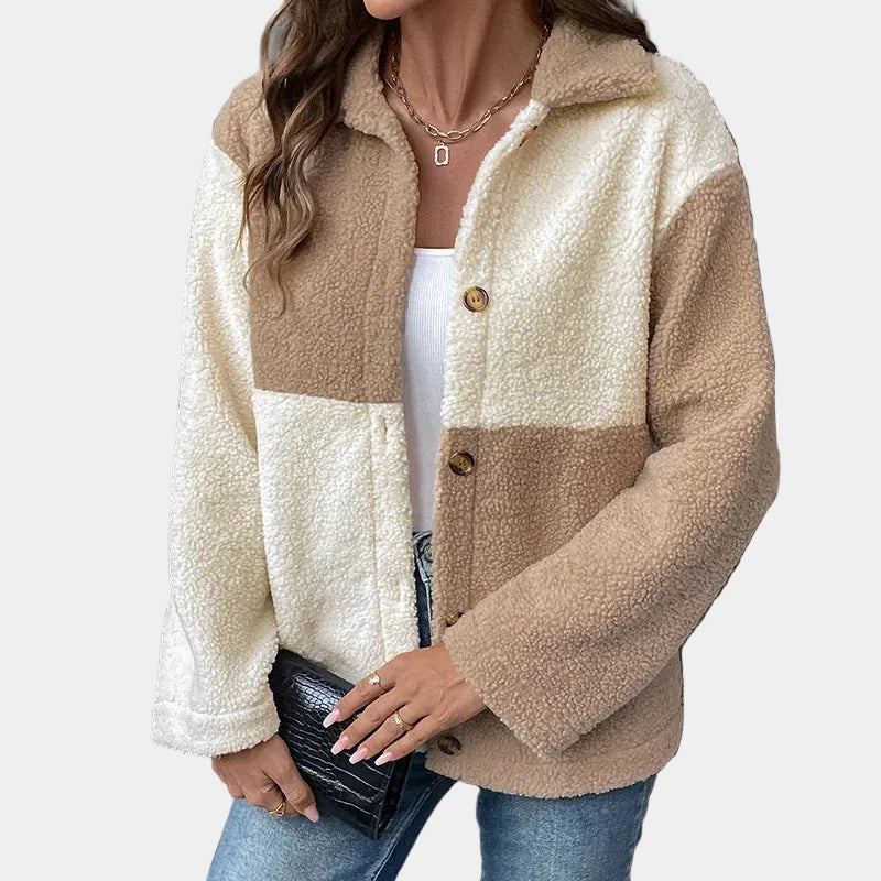 Woman wearing a beige and white sherpa jacket against a gray background